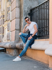 Attractive, sexy guy standing on the street in sunglasses. self-confidence, flatulence and...
