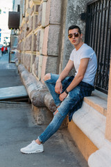 Attractive, sexy guy standing on the street in sunglasses. self-confidence, flatulence and arrogance. model, posing, portrait of a young man