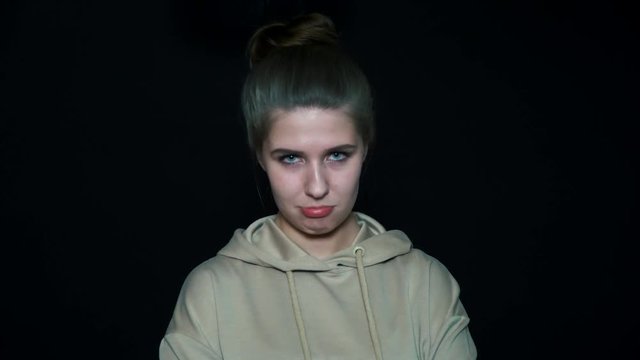 Isolated portrait of beautiful girl pouting on a black background. She's offended.