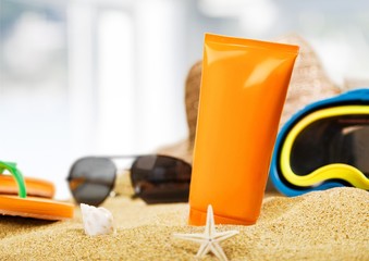 Bottle of sunscreen lotion on the sandy beach