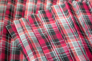 Detail of new fashion plaid pleated skirt: red, maroon, gray tartan school uniform fabric cotton/woolen material, blurred focus