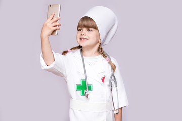 Smiling girl in medical uniform holding smartphone and take selfie