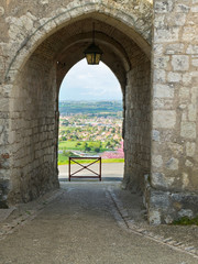 Fototapeta na wymiar View over Villeneuve-sur-Lot through a gateway of the medieval hilltop village of Pujols, Lot-et-Garonne, France. Pujols is a member of Les Plus Beaux Villages de France association.