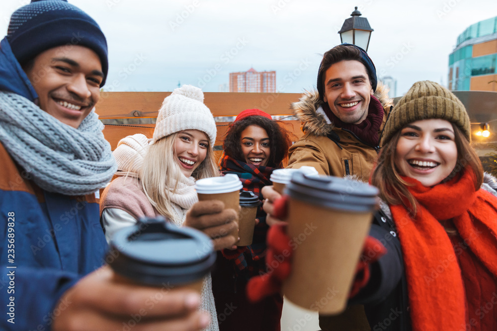 Poster happy young friends talking with each other drinking coffee outdoors winter concept.