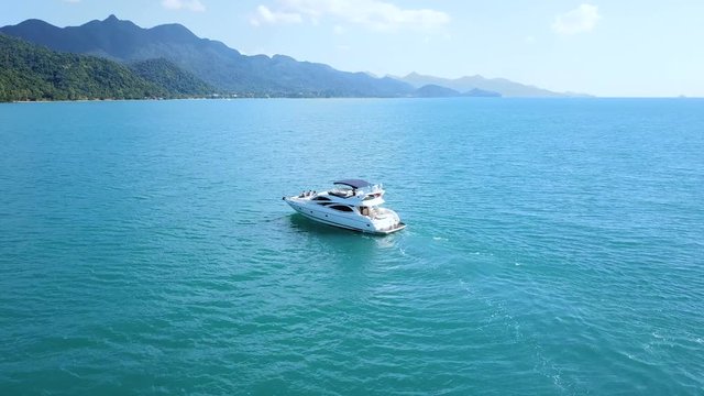 Yacht motorboat floating in blue tropical sea water near island coastline, drone aerial footage, beautiful landscape, vacation holiday leisure