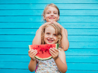 Two little sisters together with red ripe watermelon smiling