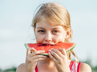 Little girl holding a slice of ripe red watermelon