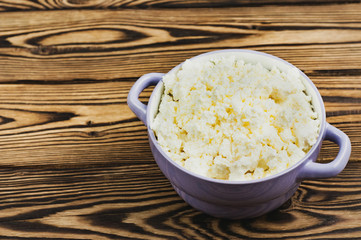Full violet ceramic bowl of fresh homemade curd on old brown wooden table