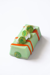 Contemporary Green Tea Mousse Cake with tropical fruits, on white background.