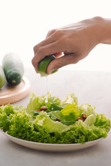 Green vegan breakfast meal in bowl with lettuce, cucumber, lime and almond. Girl holding plate with hands visible, top view. Clean eating, dieting, vegan food concept