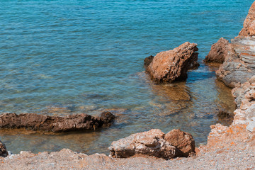 Fototapeta na wymiar Rocky seashore in Greece - still transparent water of Aegean sea, copy space.