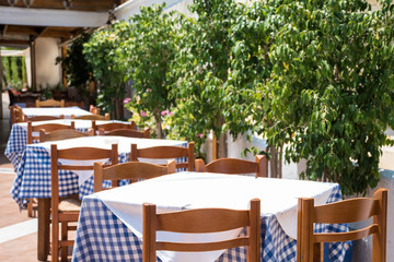 View on empty tables of an outdoor restaurant in summer.