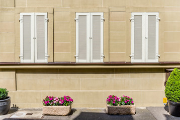 Schöne restaurierte Fassade aus Sandstein mit weißen Fensterladen und Blumenschmuck