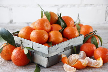 Tangerines with leaves in a wooden box.