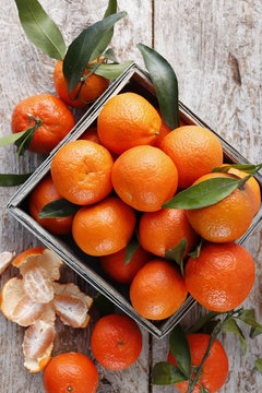 Tangerines with leaves in a wooden box.
