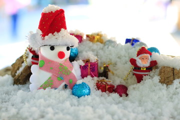 Snow man with a Christmas ornament on a snow background blur.