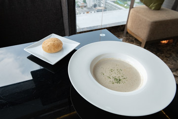A white bowl of delicious homemade cream of mushroom soup with bread.