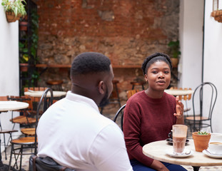 Fototapeta na wymiar Two friends talking over drinks in a trendy cafe courtyard