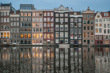 Amsterdam canal Singel with typical dutch houses illuminated in the evening. Illuminated buildings reflection in the Amsterdam canal. 