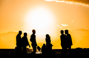 A group of people silhouette walking at the seaside at sunset in Izmir, Turkey.
