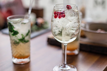 Fresh summer cocktails with bubbles, lime, mint and red berries are on the table at the sunset. Atmospheric summer drinks close up. Belarus, Minsk