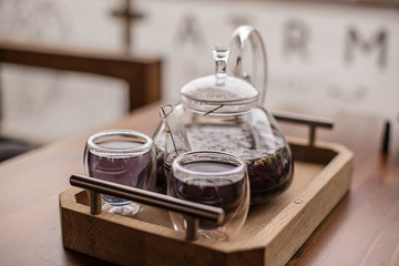 Purple floral herbal tea is poured from the brewer into the cup.