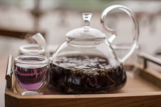Purple floral herbal tea is poured from the brewer into the cup.