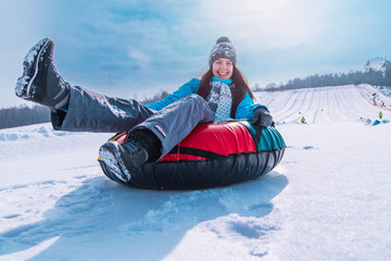 Fototapeta na wymiar young pretty woman smiling snow tubing. slide from winter hill. christmas activity concept