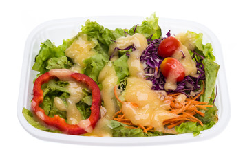 Salad with dressing in plastic container isolated on white background