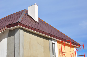 Painting house walls. House renovation with metal roof repair, house insulation, soffits and painting walls.