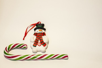 Toy snowman and sucking candy on a white background with copy space. The concept of new year backgrounds.