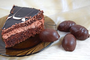 A piece of delicious chocolate cake on a brown plate and chocolates.
