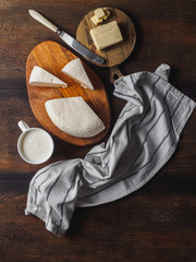Slices round homemade goat cheese on the wooden board