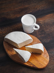 Slices round homemade goat cheese on the wooden board