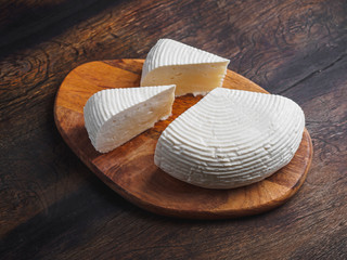Slices round homemade goat cheese on the wooden board