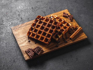 Belgian waffles with chocolate on wooden board