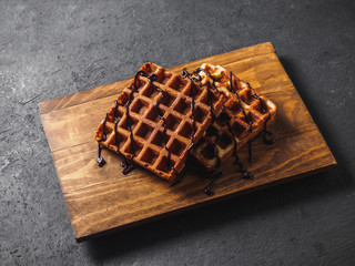 Belgian waffles with chocolate on wooden board