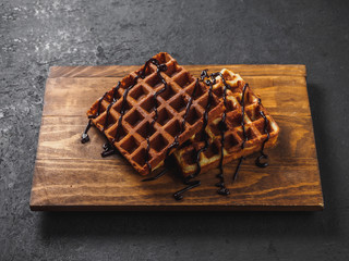 Belgian waffles with chocolate on wooden board