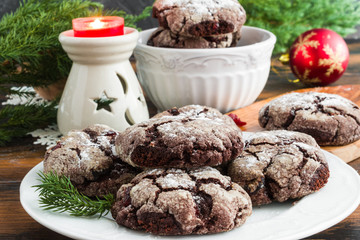 Cracked chocolate cookies with cranberries on white plate on wooden rustic table. Christmas decoration