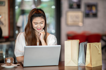 Fototapeta premium Beautiful Attractive Asian woman using computer laptop shopping online with shopping bags inside feeling so enjoy and happiness,Shopping online Concept