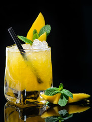 mango tiki alcoholic cocktail with mint on dark background