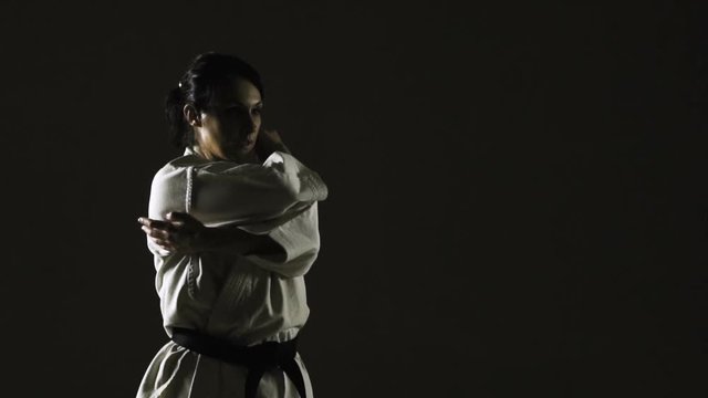 girl practicing karate, wearing kimono, on dark background. slow motion recorded at 120fps