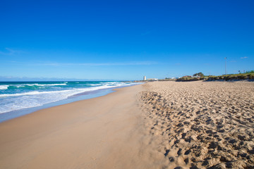 seaside of beautiful and lonely Palmar Beach with sand, turquoise ocean water and ancient tower in the horizon. In Vejer village (Cadiz, Andalusia, Spain)