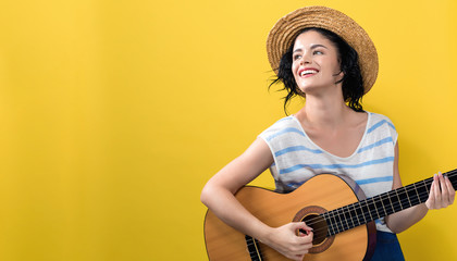 Young woman with a guitar on a yellow background