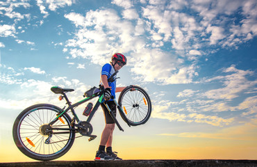 man bicyclist in trouble of front wheel of bicycle on the road, needs repairing of inflating, takes away wheel for further recondition in workshop