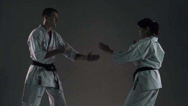 karate girl and boy having a fight, against dark background