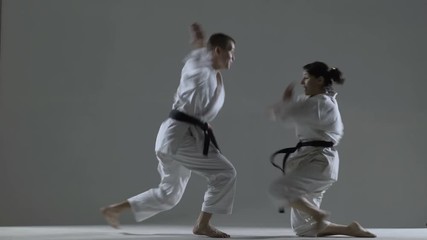 karate girl and boy having a fight, against dark background - Powered by Adobe