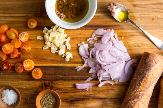 Close up of ingredients for preparing pissaladierre baguette on wooden table