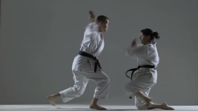karate girl and boy having a fight, against dark background