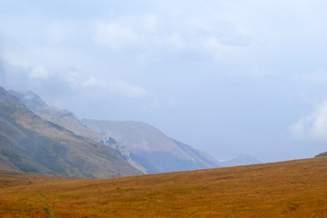 Fototapeta na wymiar steppe plateau, alpine meadow in autumn with a foggy ridge in the distance